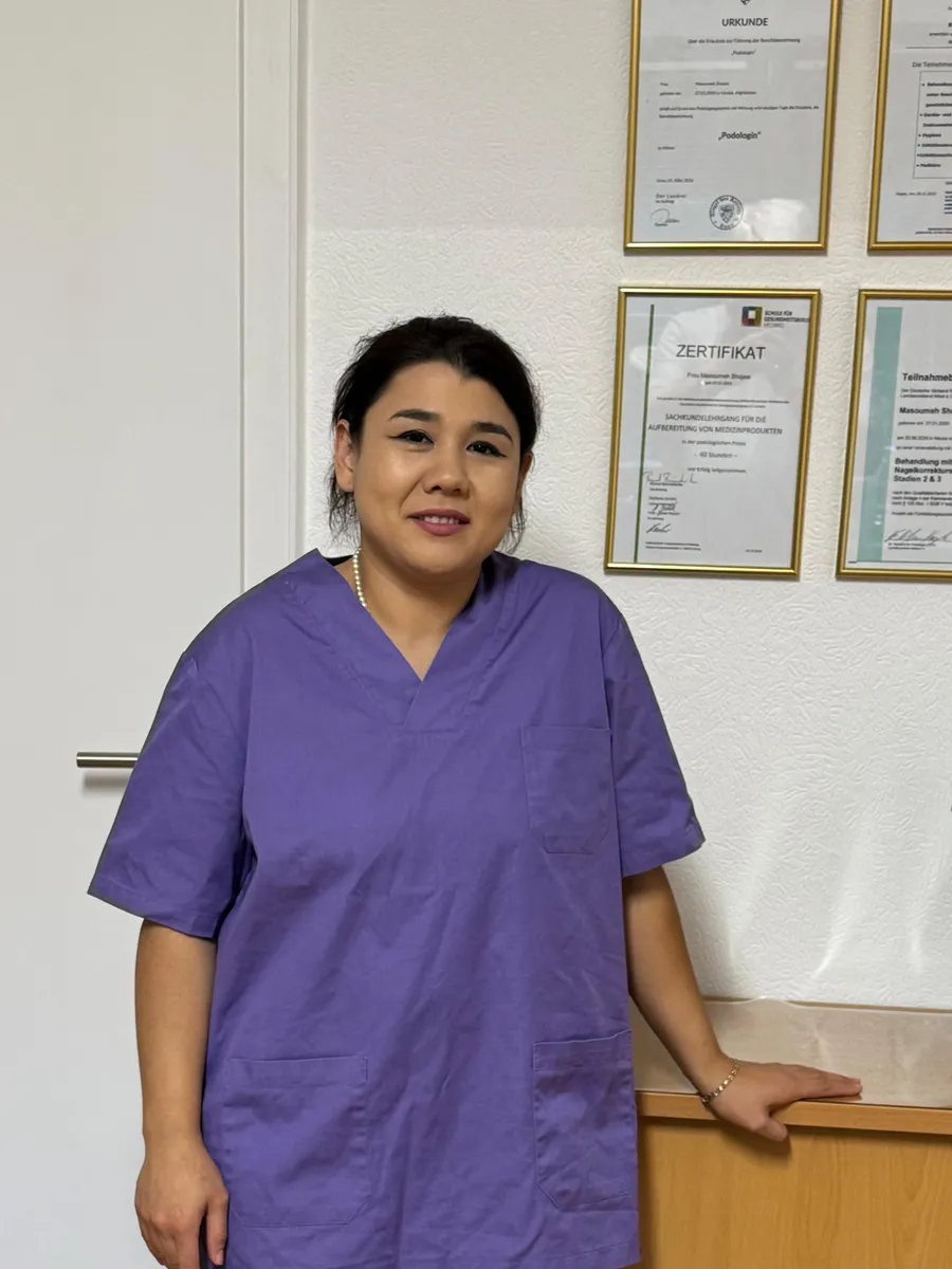 Masoumeh Shojaei steht in ihrer Praxis vor ihren Urkunden